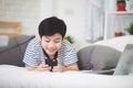 Cute asian boy rest on bed and using smart cell phone with smile Royalty Free Stock Photo