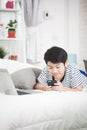 Cute asian boy rest on bed and using smart cell phone with smile Royalty Free Stock Photo