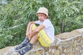 Cute Asian boy sitting on stone fence over background of green plants. Royalty Free Stock Photo