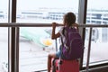 Asian child girl with backpack looking at plane and waiting for boarding in the airport Royalty Free Stock Photo