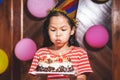 Cute asian child girl is blowing candles on delicious birthday cake in the party Royalty Free Stock Photo