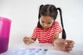 Asian child girl doing homework brushing and painting her picture with watercolor. Child doing activity when stay at home Royalty Free Stock Photo