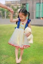 Cute Asian child girl dressed a fantasy outfit holding teddy bear and unshod walking on green grass garden with mother hand in