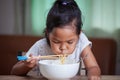 Asian child girl eating delicious instant noodles with chopsticks for her lunch in the house Royalty Free Stock Photo