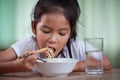 Asian child girl eating delicious instant noodles with chopsticks for her lunch in the house Royalty Free Stock Photo