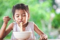 Cute asian child girl eating delicious instant noodles with fork