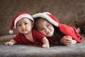 Cute asian child girl and her baby younger sister wearing christmas costume lying and relaxing on sofa bed. Royalty Free Stock Photo