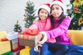 Asian child girl with her mother holding beautiful gift box and giving in Christmas celebration Royalty Free Stock Photo