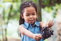 Cute asian child girl holding bunch of red grapes Royalty Free Stock Photo
