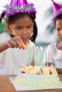 Asian child girl lighting candle on birthday cake in birthday party Royalty Free Stock Photo