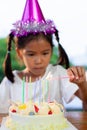 Asian child girl lighting candle on birthday cake in birthday party Royalty Free Stock Photo