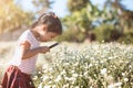 Cute asian child girl looking beautiful flower through a magnify