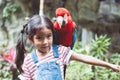 Cute asian child girl with macaw parrot in her shoulder