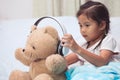 Cute asian child girl playing with her teddy bear with headphone