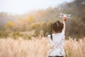 Asian child girl running and playing with toy wooden airplane in the barley field at sunset time with fun Royalty Free Stock Photo