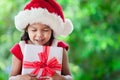 Cute asian child girl in santa red hat holding Christmas gift Royalty Free Stock Photo