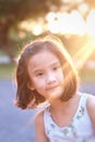 Cute Asian child girl is smiling happily in the park with sunset. Royalty Free Stock Photo