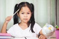Cute asian child girl thinking when doing homework Royalty Free Stock Photo