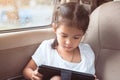 Cute asian child girl using smartphone, tablet in the car