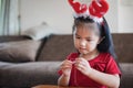 Cute asian child girl wearing christmas costume threading beads onto a string