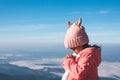 Cute asian child girl wearing sweater and warm hat making folded hands in prayer in beautiful mist and mountain background