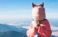 Cute asian child girl wearing sweater and warm hat making folded hands in prayer in beautiful mist and mountain background Royalty Free Stock Photo