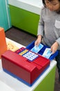 Cute Asian child, kid role playing Toy Supermarket cashier at indoor Amusement Park for kid. Play and learn activity for kid