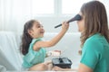 Daughter putting makeup on her mother face at home. Royalty Free Stock Photo
