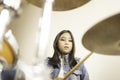 A cute Asian elementary school girl playing a drum in a music classroom