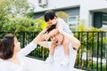 Cute Asian father piggbacking his son along with his wife in the park. Excited family spending time together with happiness. Royalty Free Stock Photo