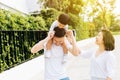 Cute Asian father piggybacking his son along with his wife in the park. Excited family spending time together with happiness. Royalty Free Stock Photo