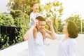 Cute Asian father piggybacking his son along with his wife in the park. Excited family spending time together with happiness. Royalty Free Stock Photo