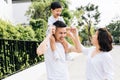 Cute Asian father piggybacking his son along with his wife in the park. Excited family spending time together with happiness. Royalty Free Stock Photo