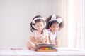 A cute Asian girl and an African kid friend are using a tablet to play games and have fun learning in the room Royalty Free Stock Photo