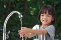 A cute Asian girl aged 4 to 8 years old, washing her hands with soap from the tap. To clean her hands Frequent hand washing with s Royalty Free Stock Photo