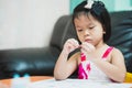 A cute Asian girl aged 4-5 years old is sitting curiously looking at the patterns on her crayon, as she does her homework. Royalty Free Stock Photo