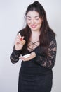 Cute Asian girl in black lace evening dress with powder and a brush in hands on white background