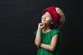 cute asian girl dressed in a green dress with a fairy hat on a black background, with an idea thinking Royalty Free Stock Photo