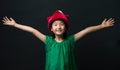 Cute Asian girl dressed in a green dress with a fairy hat and two arms wide open on a black background Royalty Free Stock Photo