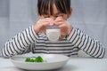 Cute Asian girl drinking a glass of milk in the morning before going to school. Little girl eats healthy vegetables and milk for