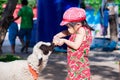 Cute Asian girl is feeding a goat`s milk. Adorable children feed the farm animals. In summer or spring. Royalty Free Stock Photo