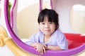 Cute Asian girl looked out of the window of a toy car. Child smiles sweet and bright. Children play in amusement park.