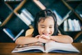 Cute asian girl reading a book and smiling teeth white while in the live room Royalty Free Stock Photo