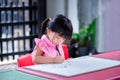 Cute Asian girl sitting on a drawing of myself on piece of paper that is pinned on plywood sheet. Child do art. Kid is cutting a l