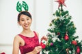 Cute Asian girl teen decorate Christmas tree for new year holiday event happy smile Royalty Free Stock Photo