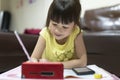 Cute Asian girl using smartphone to study online with teacher on video call at home. homeschooling, distance learning. Royalty Free Stock Photo