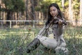 Cute asian girl with a violin on the grass on blurred woods background Royalty Free Stock Photo