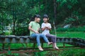 Cute Asian girls sitting together on wooden bridge. Two happy young cute girls are having fun outdoors. Asian siblings playing in Royalty Free Stock Photo