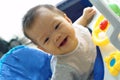 Cute Asian infant smiling on baby walker in her room.