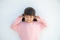 Cute Asian kid girl covered ears the fingers and gesturing that not want to listen on white background